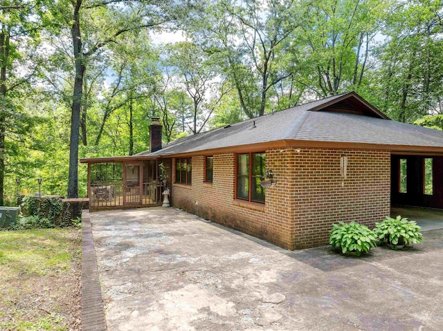 132 Rosecrest, Spartanburg, SC 29303 - view of home's exterior with roof with shingles, a chimney, brick siding, driveway, and a patio