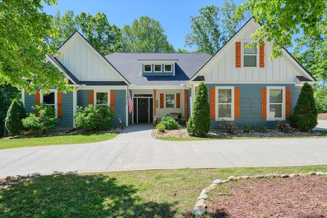 view of front of house with board and batten siding, roof with shingles, and a front yard