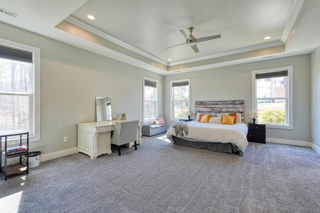 carpeted bedroom with a raised ceiling, multiple windows, ornamental molding, baseboards, and recessed lighting