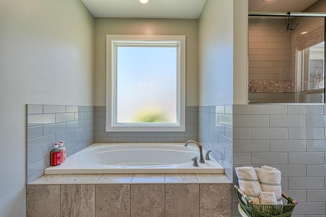 bathroom featuring a stall shower and a bath