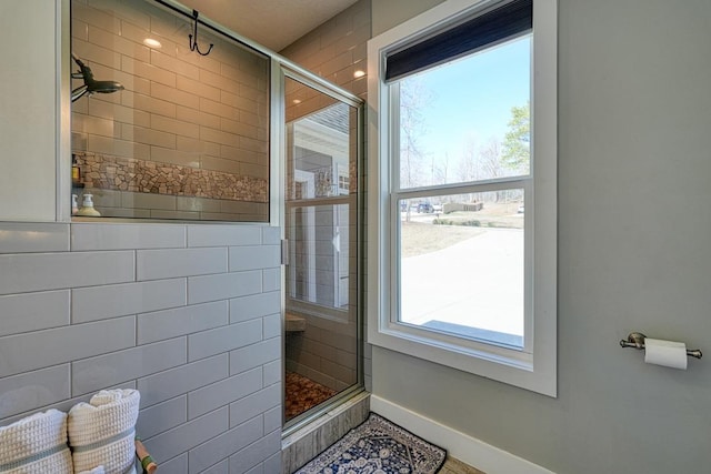 bathroom with tiled shower and baseboards