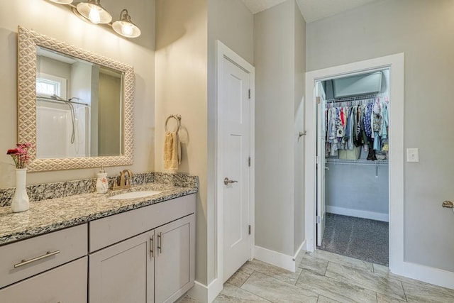 bathroom featuring baseboards, vanity, and a spacious closet