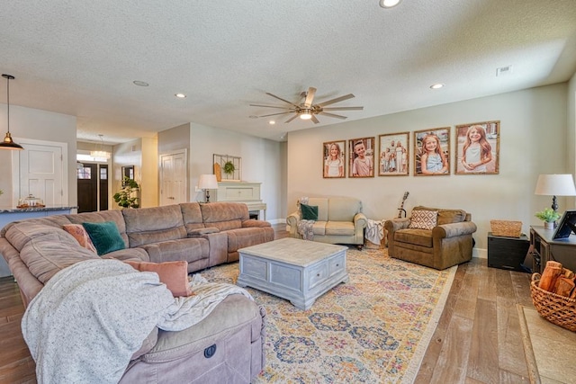 living area with light wood-type flooring, a textured ceiling, a ceiling fan, recessed lighting, and baseboards