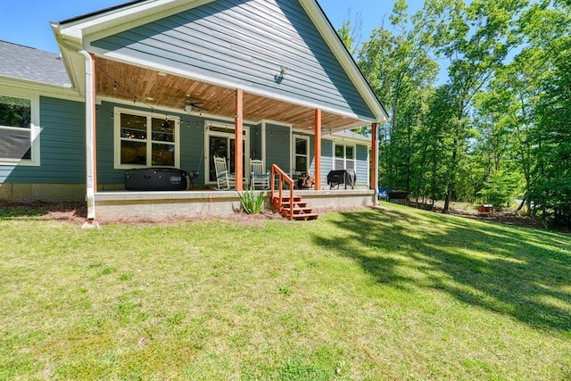 rear view of property featuring a ceiling fan, a yard, and a porch