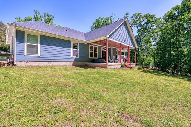 view of front of home featuring a front yard, roof with shingles, and covered porch