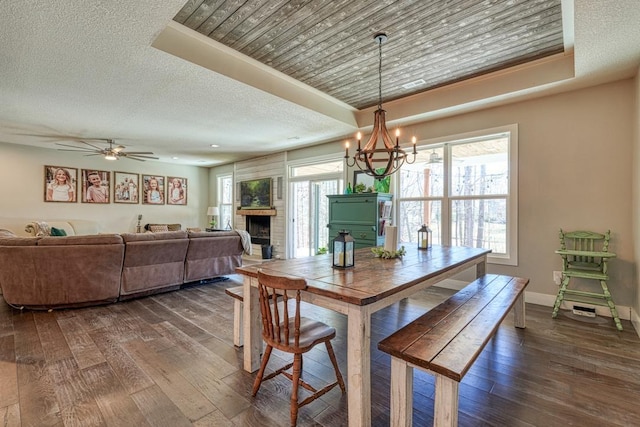 dining area with dark wood-style floors, a chandelier, a fireplace, baseboards, and a textured ceiling
