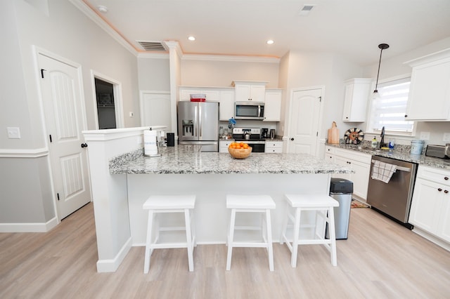 kitchen with appliances with stainless steel finishes, a center island, light wood-style flooring, a kitchen bar, and white cabinets