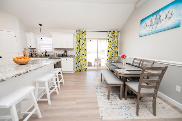 dining area featuring light wood finished floors, plenty of natural light, and vaulted ceiling