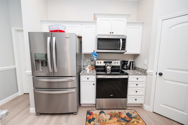 kitchen featuring stainless steel appliances, light wood-style flooring, white cabinetry, light stone countertops, and baseboards