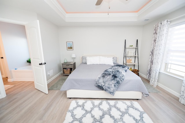 bedroom with a raised ceiling, wood finished floors, ornamental molding, baseboards, and a ceiling fan