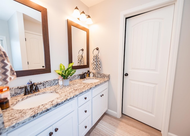 full bath featuring double vanity, wood finished floors, and baseboards