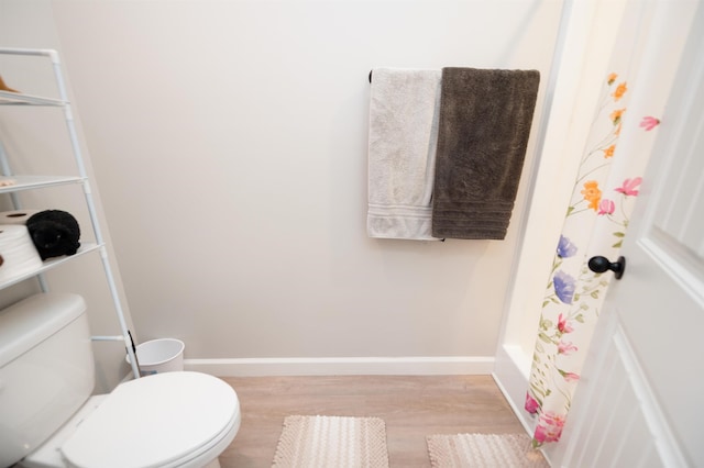 full bathroom with wood finished floors, toilet, and baseboards