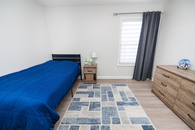 bedroom with multiple windows, light wood-style flooring, and baseboards