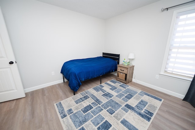 bedroom featuring multiple windows, wood finished floors, and baseboards