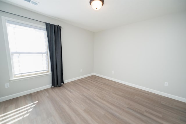 spare room with plenty of natural light, light wood-style floors, and baseboards