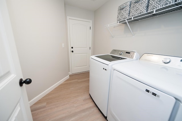 washroom featuring washing machine and clothes dryer, light wood-style floors, and baseboards