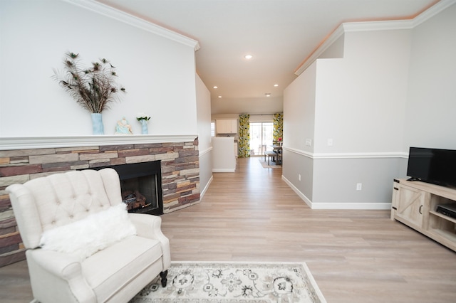living room featuring wood finished floors, baseboards, ornamental molding, a fireplace, and recessed lighting