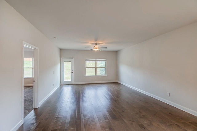 spare room featuring a ceiling fan, baseboards, and dark wood finished floors