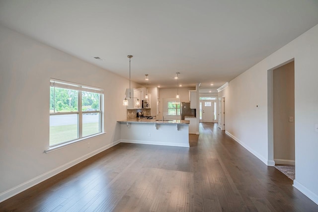 kitchen with stainless steel appliances, a peninsula, white cabinets, and dark wood-style flooring
