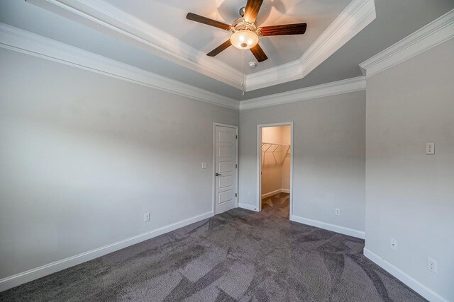 carpeted empty room with ceiling fan, a raised ceiling, crown molding, and baseboards