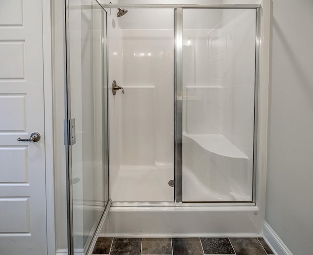 bathroom featuring a shower stall and baseboards