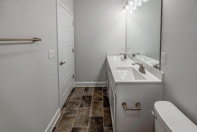 full bathroom with double vanity, toilet, and baseboards