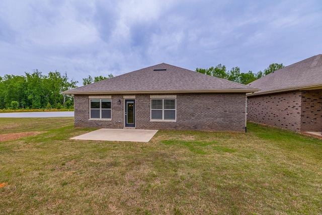 back of house featuring a patio, a yard, brick siding, and roof with shingles