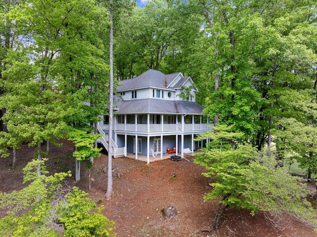 view of front of house with a shingled roof, a patio area, a wooden deck, and stairs