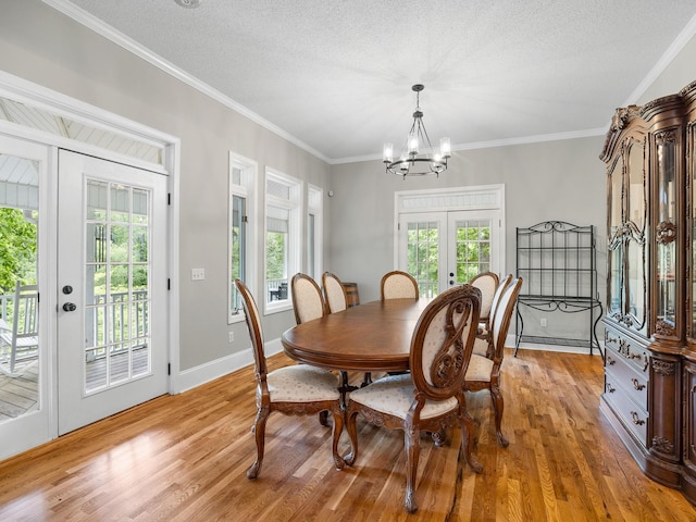 dining area with french doors, light wood-style floors, a chandelier, healthy amount of natural light, and ornamental molding