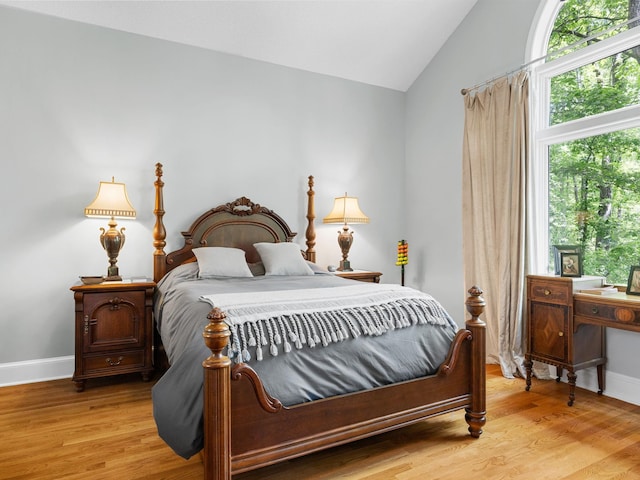bedroom with lofted ceiling, light wood-type flooring, and baseboards