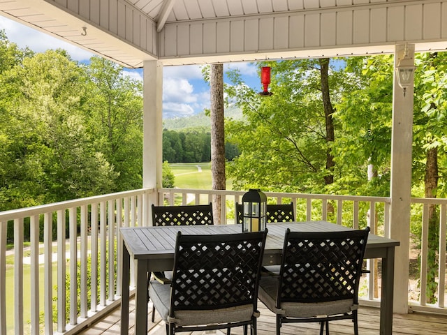 wooden deck with outdoor dining space and view of scattered trees