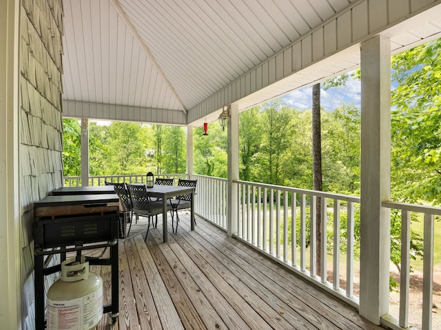 wooden terrace with outdoor dining space and view of wooded area