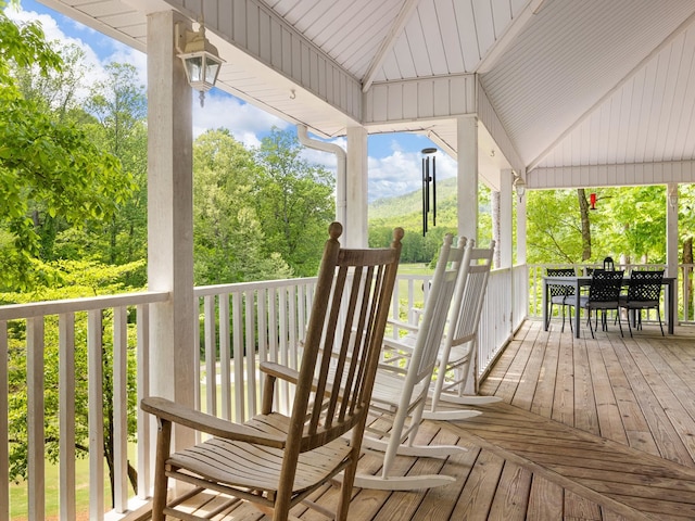 wooden terrace featuring outdoor dining area and view of scattered trees