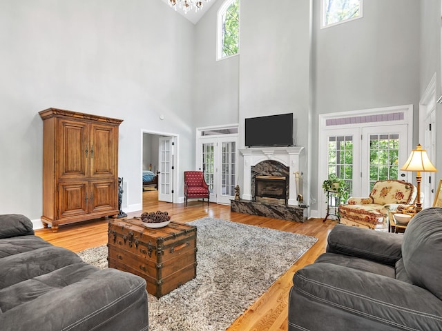 living room with high vaulted ceiling, light wood finished floors, a fireplace, and french doors