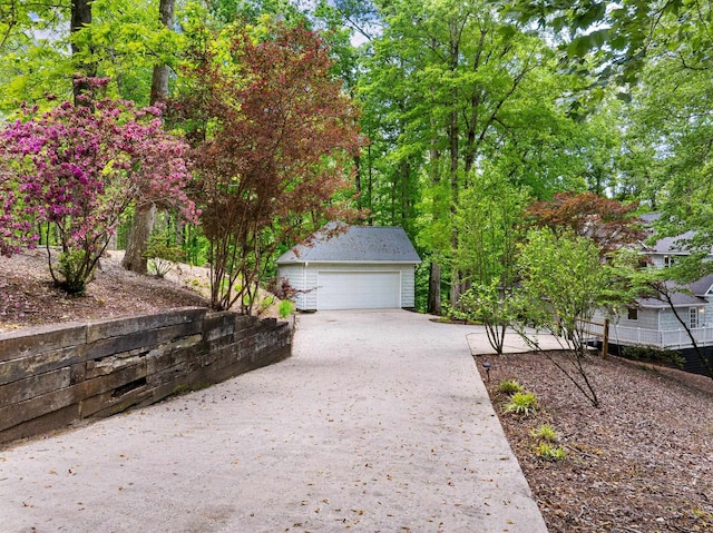 view of side of home with a garage, an outdoor structure, and concrete driveway