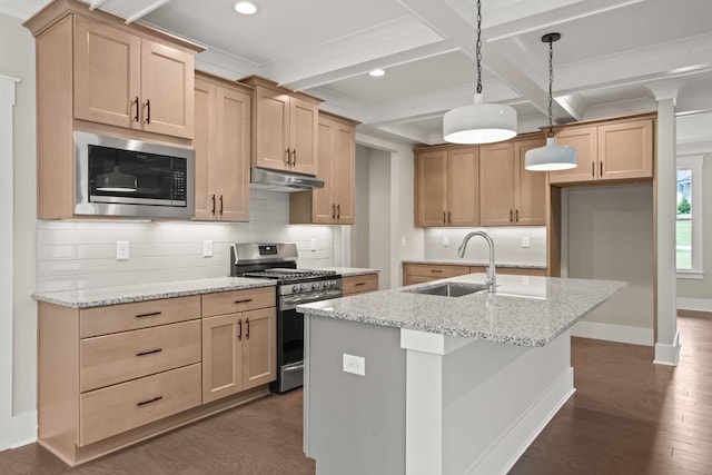 kitchen with appliances with stainless steel finishes, a sink, under cabinet range hood, beam ceiling, and dark wood-style flooring