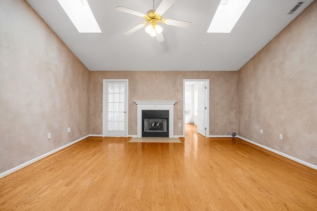 2 Birch Tree, Greer, SC 29651 - unfurnished living room featuring a skylight, light wood-style flooring, baseboards, a fireplace with flush hearth, and vaulted ceiling