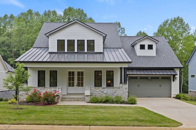 modern farmhouse with a standing seam roof, a shingled roof, covered porch, a front yard, and concrete driveway