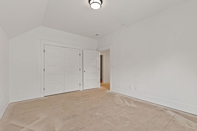 unfurnished bedroom with a closet, baseboards, and vaulted ceiling