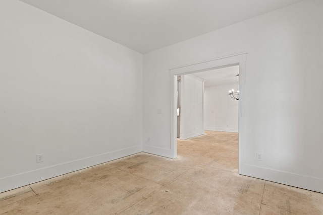 unfurnished room featuring baseboards, a chandelier, and concrete flooring