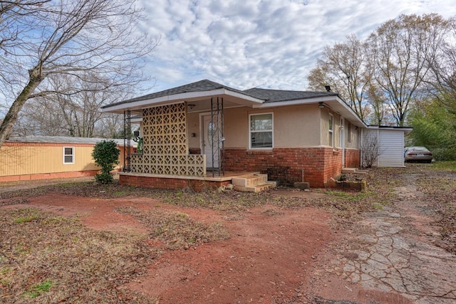 view of front of house with brick siding, stucco siding, driveway, and a porch