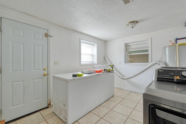 laundry area featuring light tile patterned flooring, a textured ceiling, water heater, and washing machine and clothes dryer