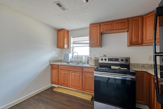 kitchen featuring stainless steel electric range, a sink, dark wood-style flooring, brown cabinetry, and baseboards
