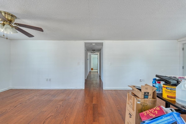 spare room featuring wood finished floors, a textured ceiling, a ceiling fan, and baseboards
