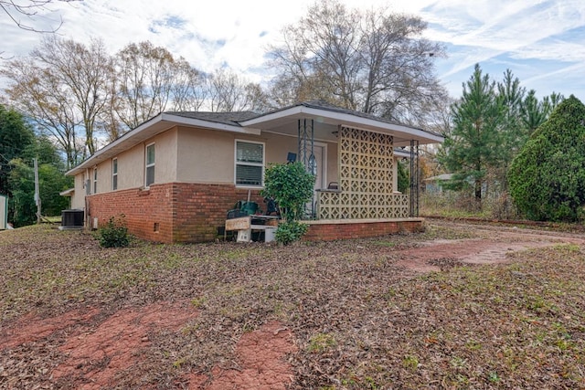 view of property exterior featuring stucco siding, central AC, and brick siding