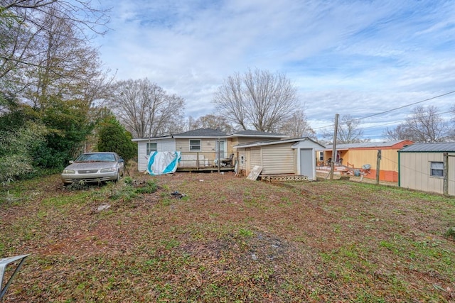 rear view of house with an outdoor structure, a shed, and a wooden deck
