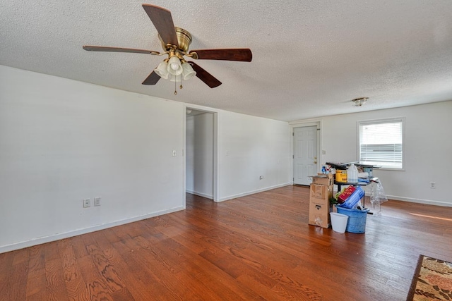empty room with a textured ceiling, ceiling fan, wood finished floors, and baseboards