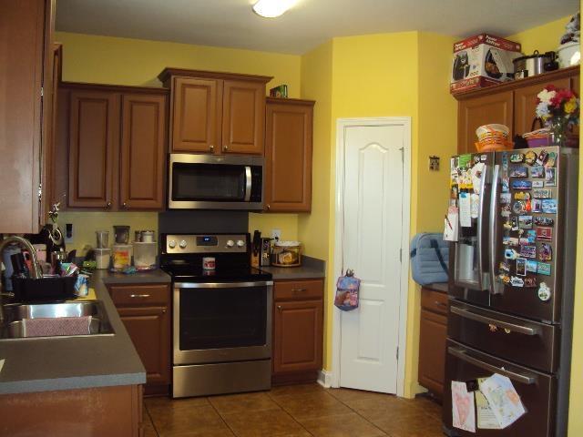 474 Slate, Boiling Springs, SC 29316 - kitchen with appliances with stainless steel finishes, a sink, dark tile patterned flooring, dark countertops, and brown cabinets