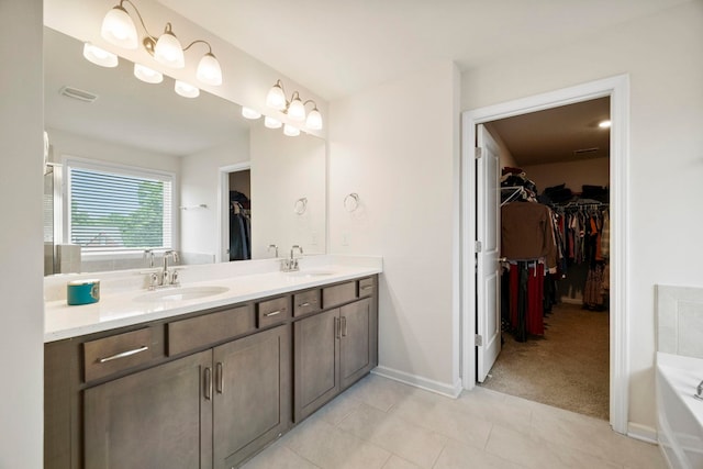 full bath with tile patterned flooring, a tub, double vanity, a spacious closet, and baseboards