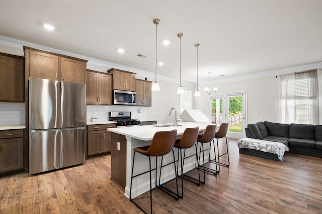 kitchen featuring stainless steel appliances, a kitchen bar, a sink, ornamental molding, and decorative backsplash